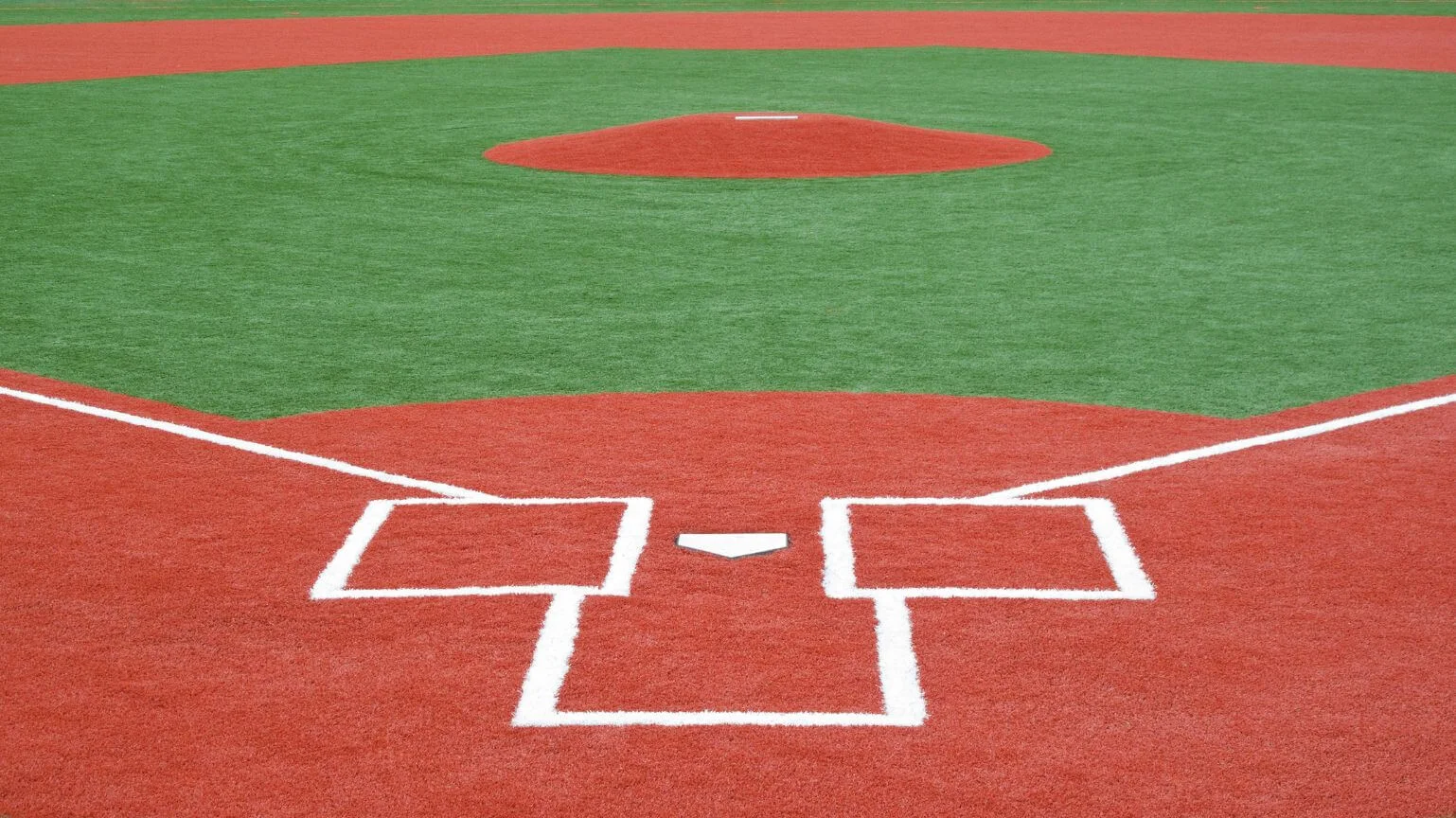 An outdoor baseball field in Arizona featuring red synthetic turf for the base paths and green synthetic turf for the infield. 