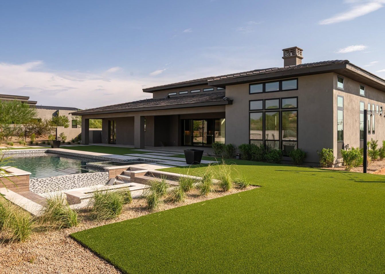 modern house with pool and artificial grass installed around the pool and in the side yard. Artificial grass and landscaping done by Surprise Artificial Grass Co