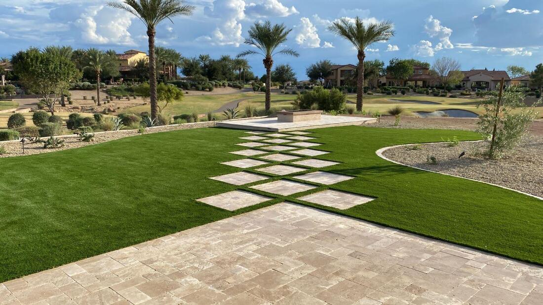 Travertine pavers surrounded by artificial turf in a backyard in Surprise, Arizona